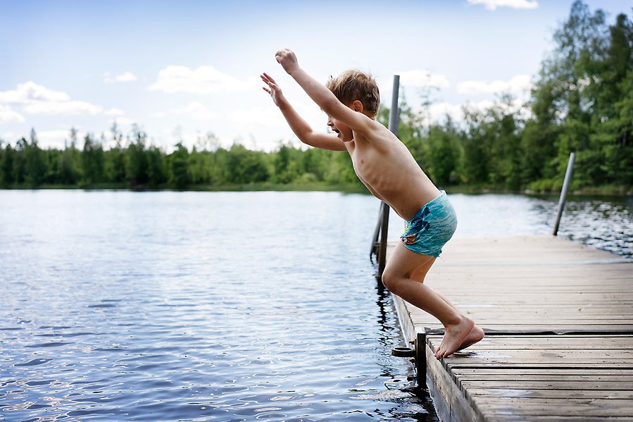 Barn hoppar från brygga ner i sjön